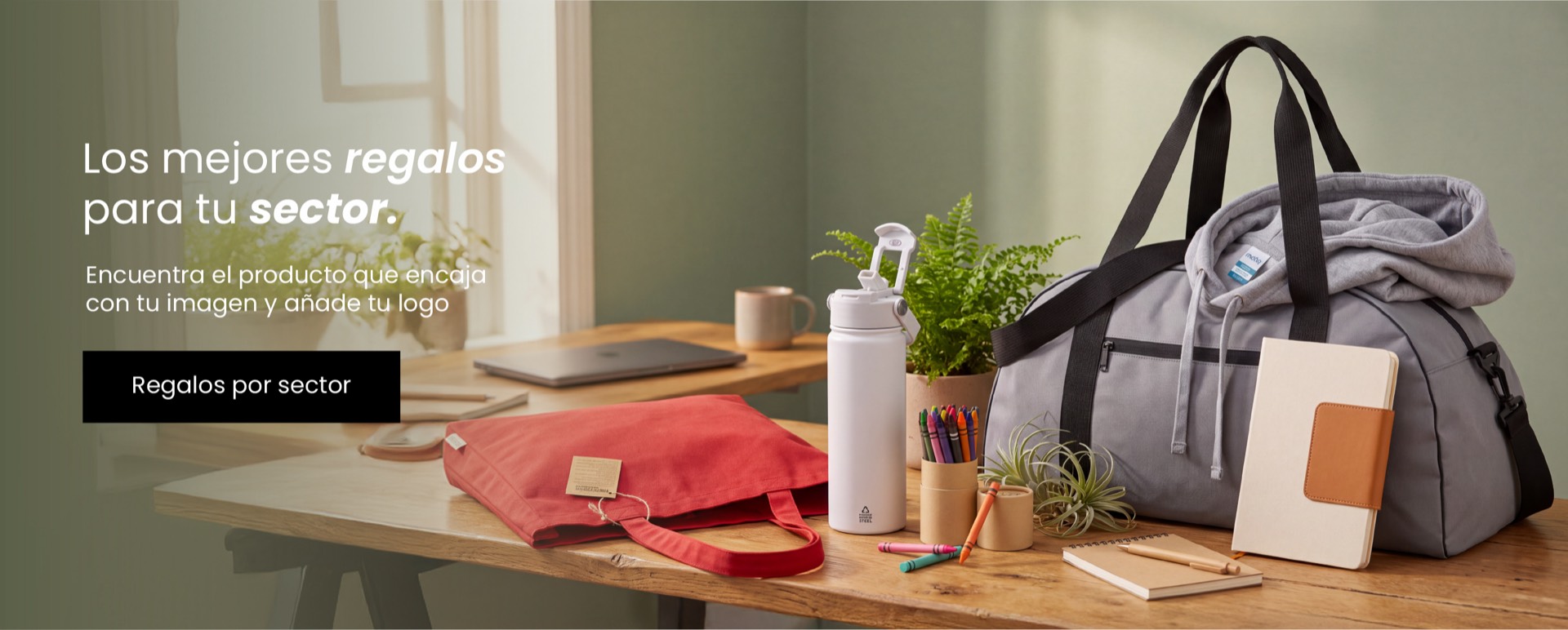 Selección de regalos promocionales personalizados sobre una mesa, incluyendo balón, mochila, sudadera, botella reutilizable, libreta, peluche y accesorios corporativos